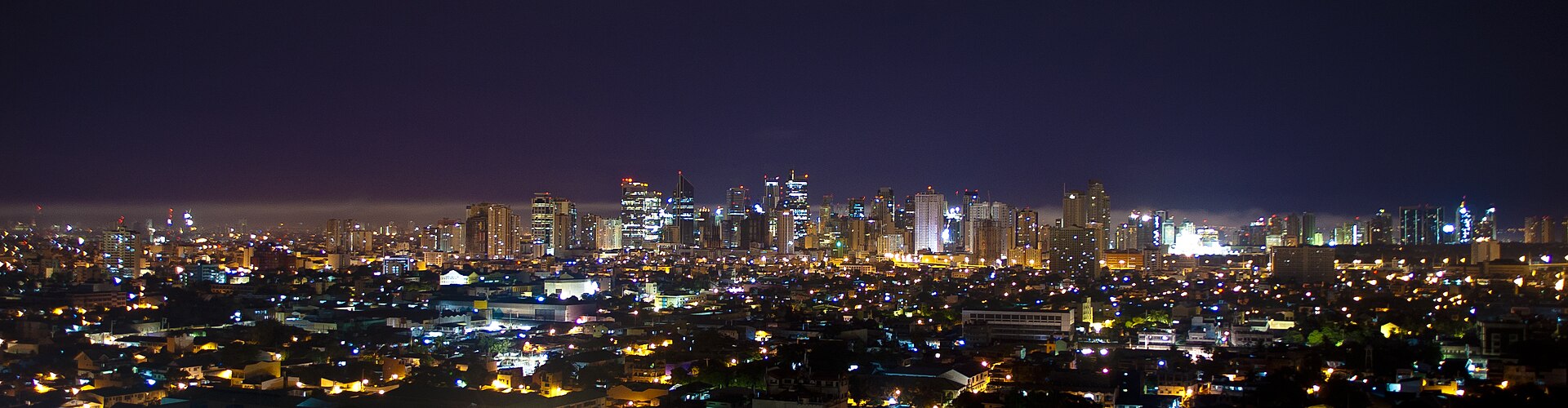 Makati at night: the skyline towers lit above the low-rise city, seen across the metro